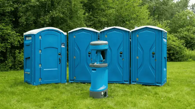 Four blue portable toilets and a matching hand washing station on grass near trees, a common sight at local outdoor events in Colorado Springs, CO